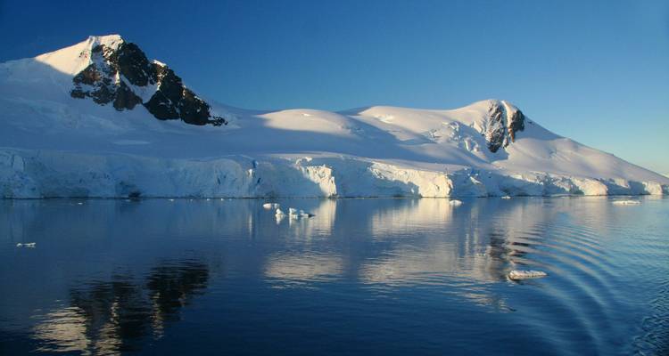 Montagnes enneigées se reflétant sur l'eau.