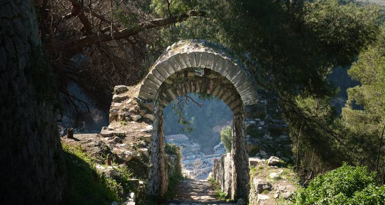 Arcade en pierre avec vue sur un village en contrebas.