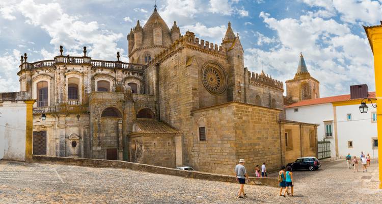 Église historique à Évora avec des touristes explorant la rue pavée.