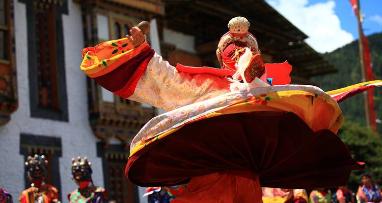 Danseur masqué en costume vibrant qui tourne pendant un festival traditionnel bhoutanais