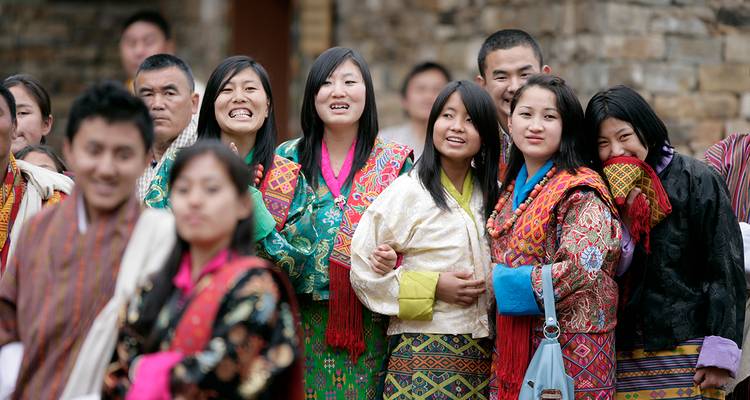 Groupe de femmes bhoutanaises souriantes vêtues de kira colorés regardant les festivités