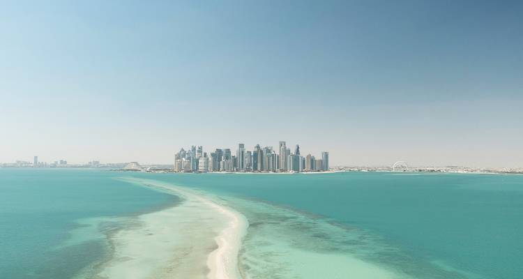 Cityscape view of the Doha skyline from a distance over water.