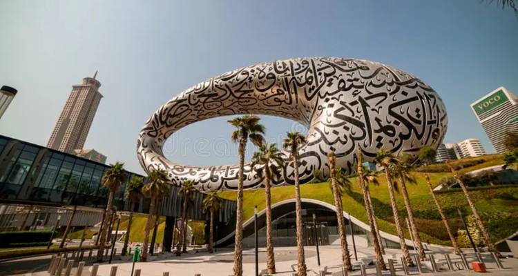 Bâtiment futuriste avec calligraphie arabe et palmiers au premier plan.