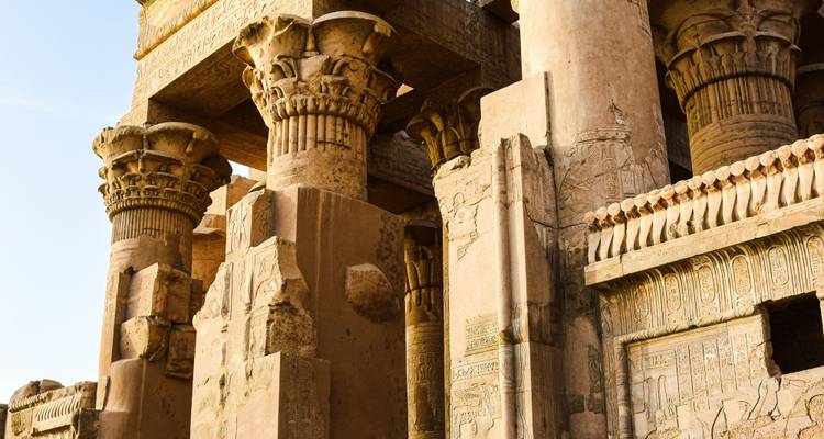 Columnas detalladas cubiertas de jeroglíficos del Templo de Kom Ombo iluminadas por la cálida luz del sol.
