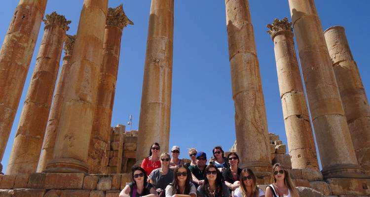 Grupo de turistas posando en escaleras de piedra rodeados de imponentes columnas romanas en las ruinas de Jerash.