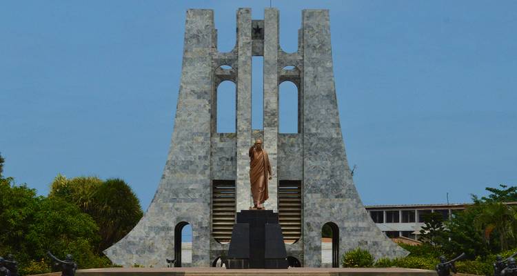 Statue devant un grand monument commémoratif.
