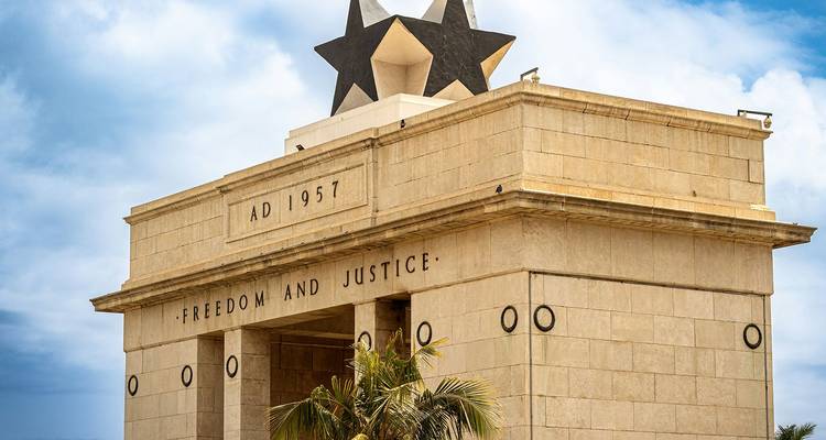 Stone monument topped by a black star with the inscription “AD 1957 • FREEDOM AND JUSTICE” against a partly cloudy sky.