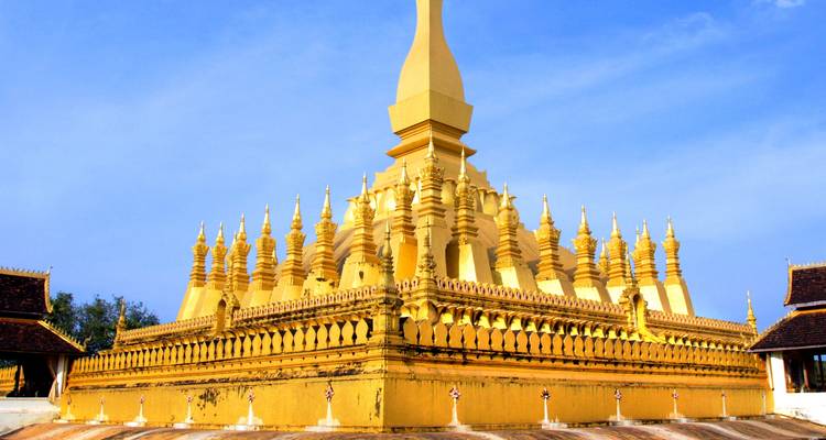 Gouden stupa met ingewikkelde architectuur onder een blauwe hemel.