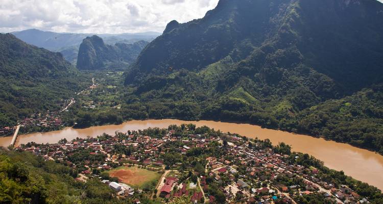 Panoramic view of a river bend surrounded by lush greenery and mountains.