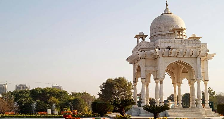 Pavillon en marbre blanc dans un cadre de jardin.