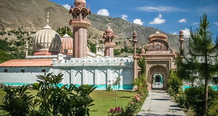 Belle mosquée avec un aménagement paysager luxuriant sur fond de montagnes.
