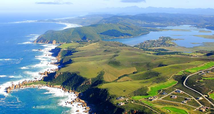 Vista aérea de un paisaje costero con mar azul y colinas verdes.