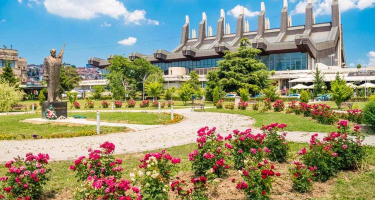 Un parc avec des fleurs roses en fleurs et un bâtiment d'architecture moderne en arrière-plan.