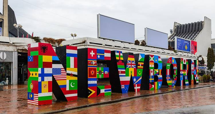 La sculpture 'NEWBORN' peinte avec des drapeaux internationaux à l'extérieur par jour de pluie.
