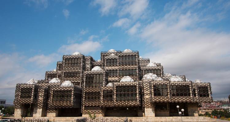 Bâtiment de bibliothèque publique à l'architecture unique contre un ciel partiellement nuageux.