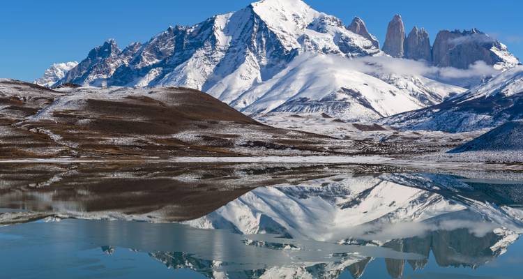 Des sommets montagneux enneigés avec un reflet clair dans un lac.