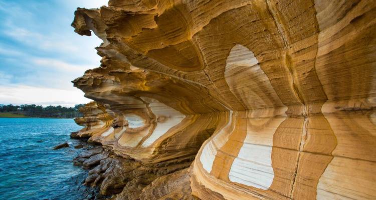 Close-up van kleurrijke rotsformaties bij de zee, met lagen en unieke texturen.