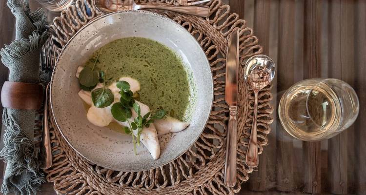 Gerecht met groene soep en witte garnering.