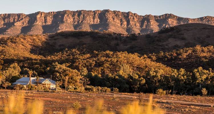 Huis voor een bergketen bij zonsondergang.
