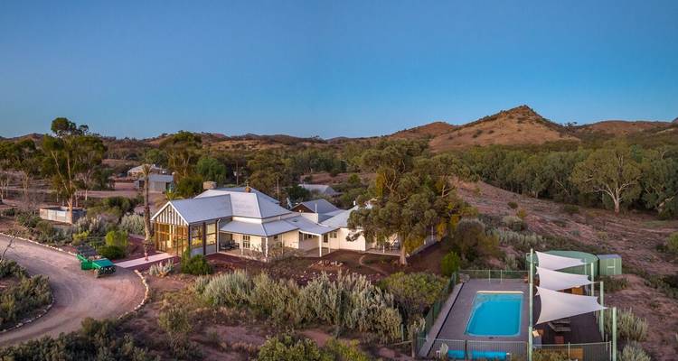 Une vue aérienne d'une maison avec une piscine sur un fond de collines.