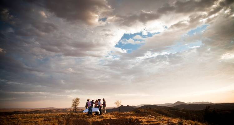 Groep mensen die een picknick hebben op een heuvel met panoramisch uitzicht op de bergen.
