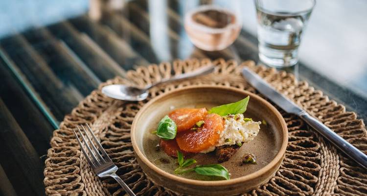Een gourmetgerecht met citrus en garnituur op een rustieke tafelschikking.