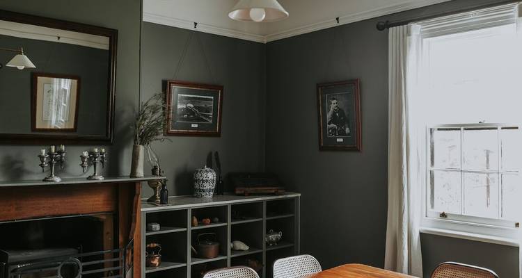 Salle à manger avec murs sombres, décoration vintage et mobilier en bois.