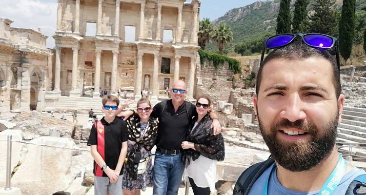 Familia posando con un guía frente a ruinas antiguas.