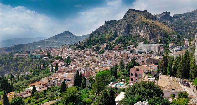 Hangsicht über die malerische Stadt Taormina, umgeben von grünen Gipfeln und Meeresblicken.