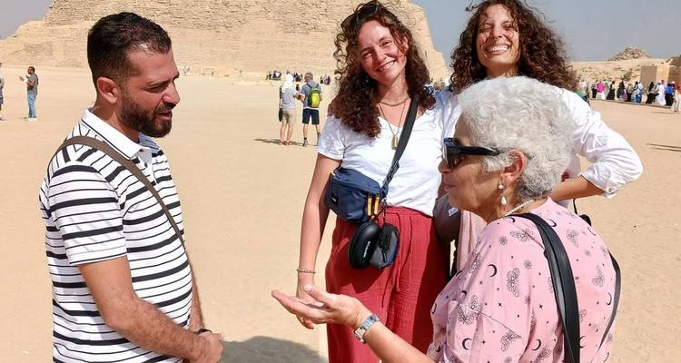 Toeristen in gesprek met een gids bij de piramides.