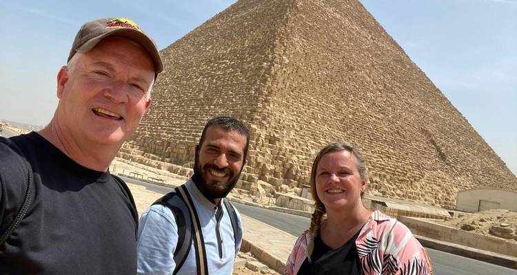 Twee mannen en een vrouw poseren voor een piramide.