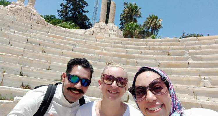 Drie mensen poseren in een antiek amfitheater.