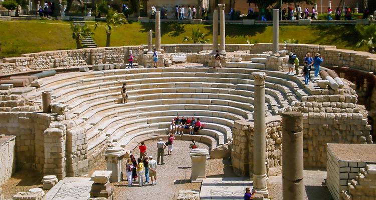 People exploring an ancient stone amphitheater.

Translation to Dutch:
Mensen die een oud stenen amfitheater verkennen.