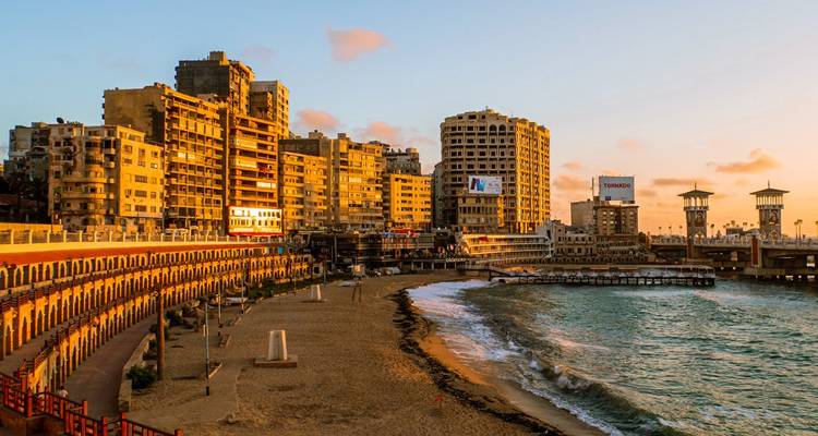 Stadsgezicht met een strand en boulevard bij zonsondergang.