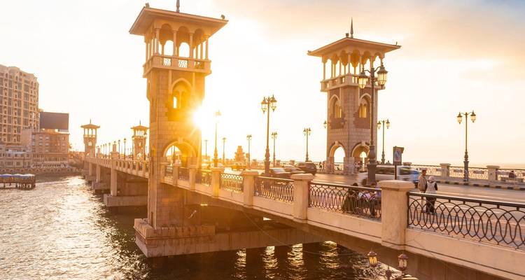 Brug over water met de zon die erachter ondergaat.
