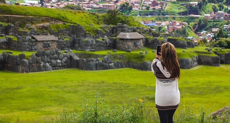 Vrouw die een foto maakt van een oude ruïne met groene velden.