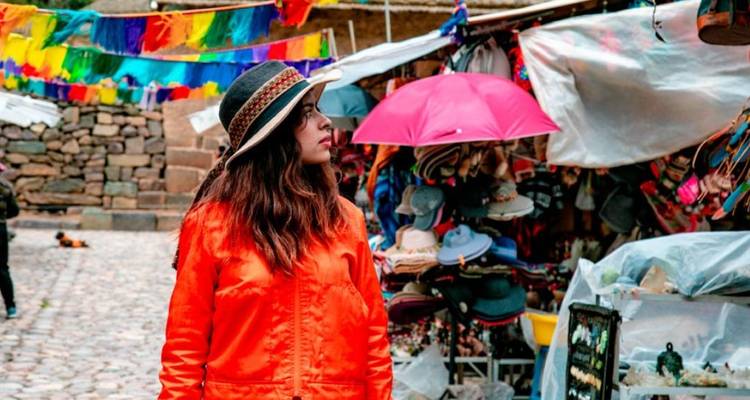 Vrouw die door een kleurrijke markt loopt met traditionele items te koop.