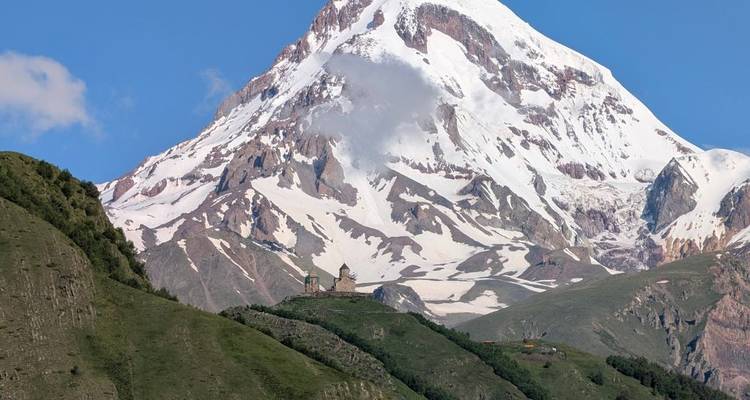 Gergeti Trinity Church gelegen onder een met sneeuw bedekte berg.