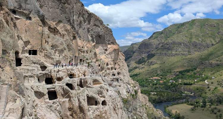 Vardzia grottenklooster in een klif met mensen die het verkennen.