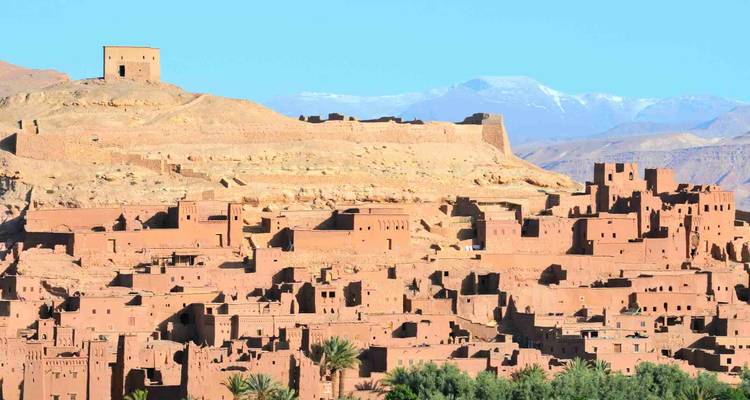 Eine befestigte antike Stadt mit Bergen im Hintergrund.