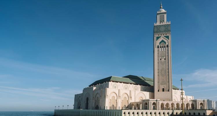 Eine Moschee am Meer unter klarem blauen Himmel.