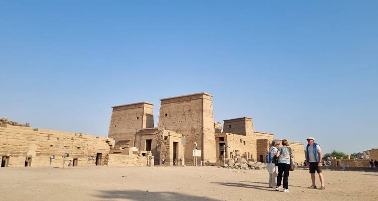 Toeristen die oude tempelruïnes verkennen onder een heldere hemel.