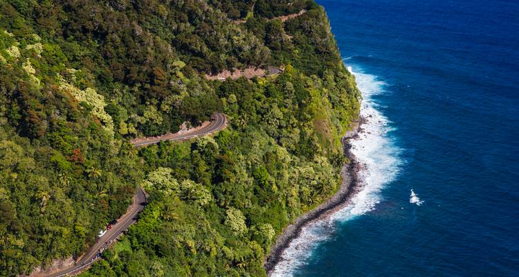 Vue aérienne d'une route côtière sinueuse longeant des falaises verdoyantes au-dessus des eaux bleu profond du Pacifique.