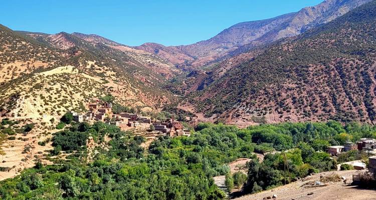 Vallei met verspreide dorpen en weelderig groen, omringd door ruige bergen.