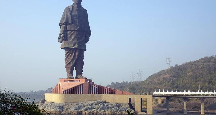 Une grande statue sur un socle avec des montagnes en arrière-plan.