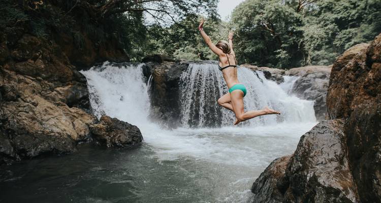 Personne en plein saut devant une cascade.
