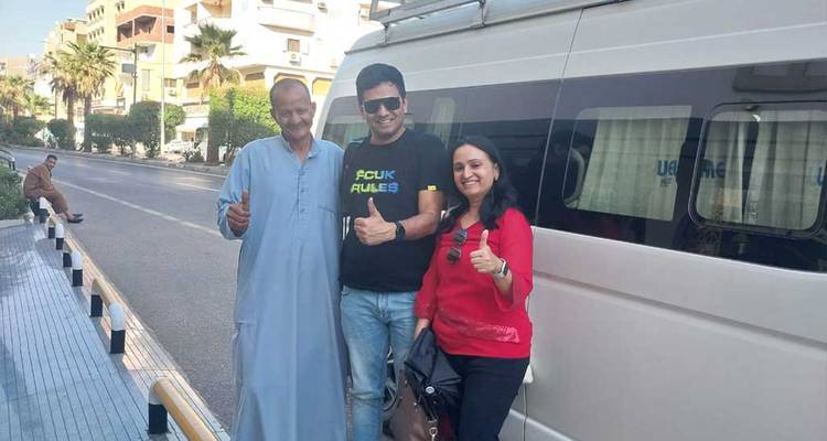 Deux touristes posant avec un guide local près d'une camionnette.