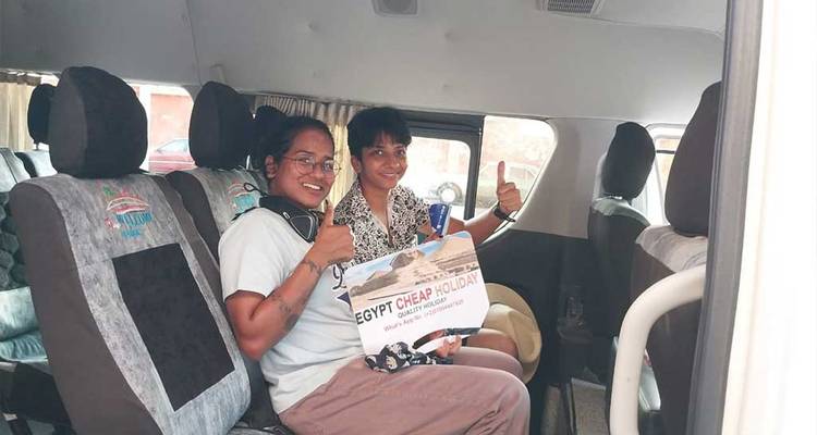 Des touristes dans un van tenant un panneau de visite.