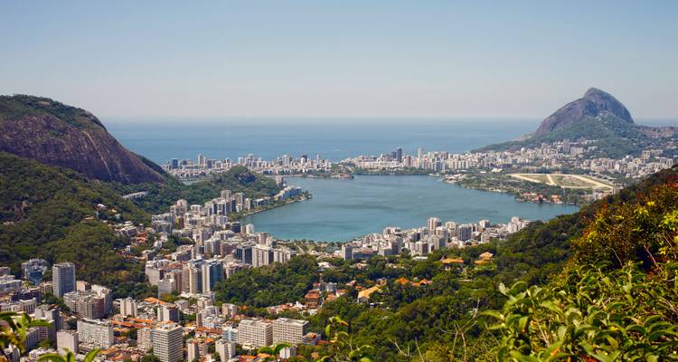 Vue panoramique urbaine avec un grand lac et des collines verdoyantes environnantes.