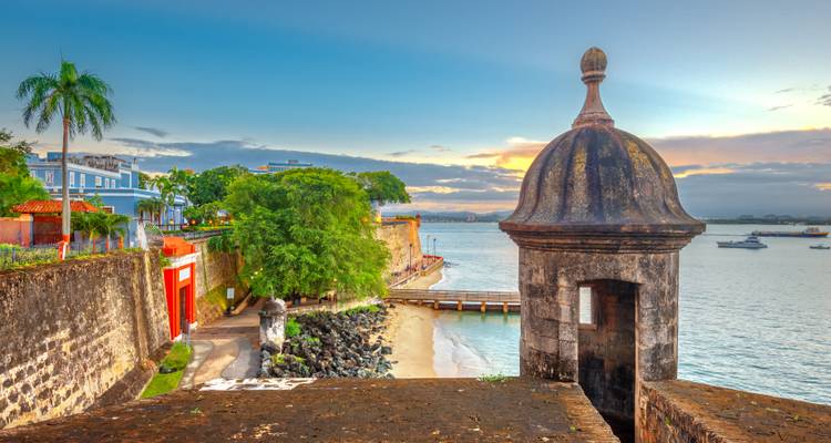 Fort historique surplombant une mer calme avec une tour de guet en pierre.